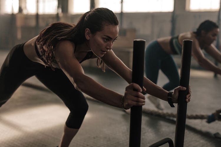 A person working out in a gym lunging forward while grabbing two parallel bars