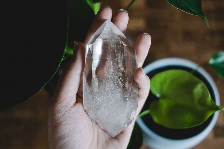 A closeup of a hand holding a large clear crystal