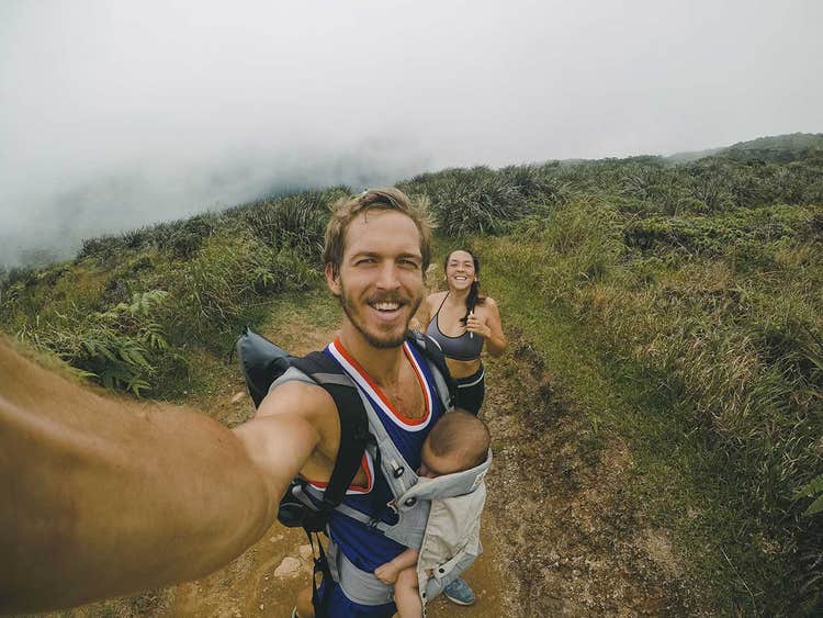 dad taking photo of mom and baby while hiking on a mountain