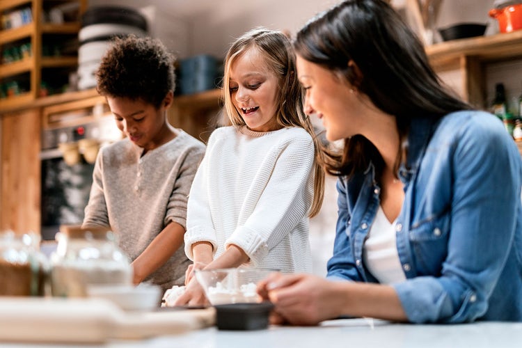 woman-teaching-two-children-how-to-cook