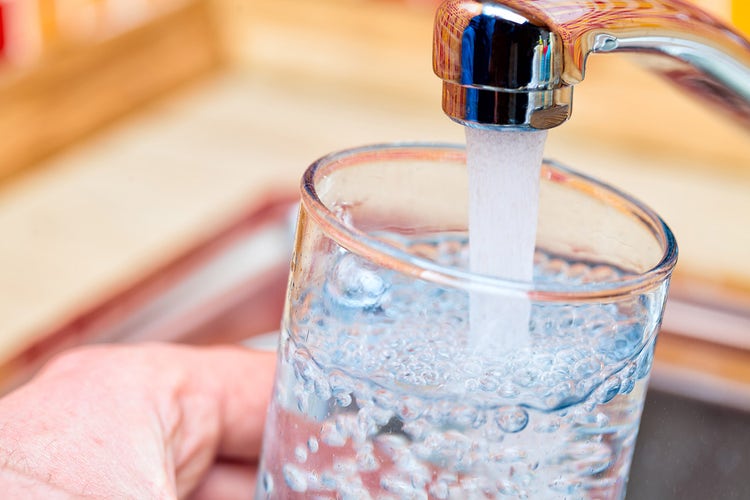 Closeup of a sink faucet filling up a glass of water