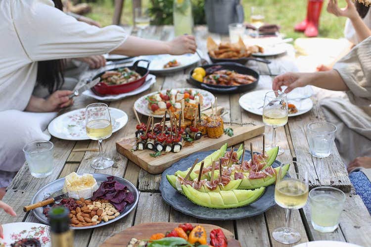 close up of table with food and people eating together outside
