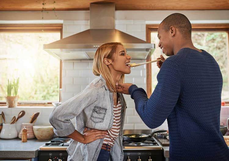 man feeding woman in kitchen