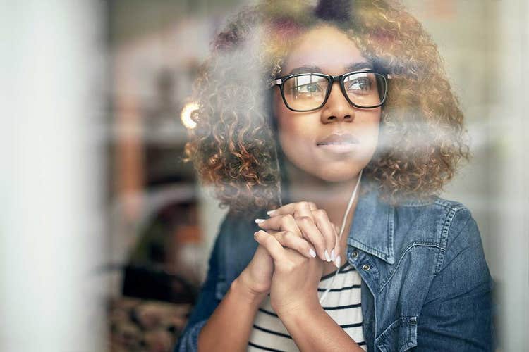 close-up of woman in glasses looking out the window listening with headphones