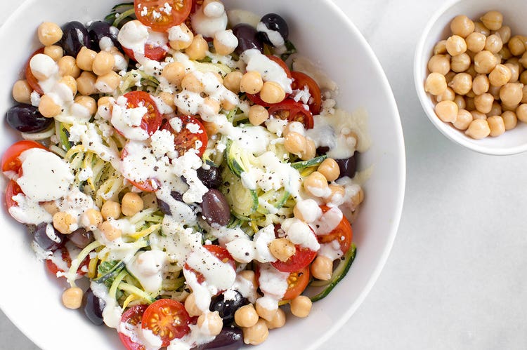 A white bowl containing Mediterranean zucchini noodle and tomato salad