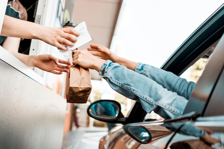 Woman purchasing coffee and food at a drive-through