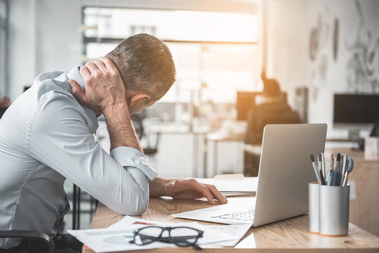 man-massaging-his-neck-at-his-desk